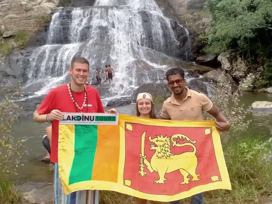 Travelers holding a flag at a scenic waterfall day tour with a private driver in Sri Lanka.